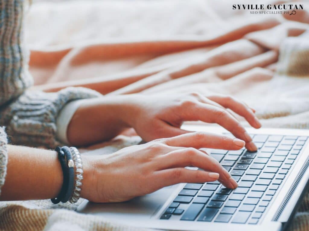 Person typing on a laptop with a cozy background.