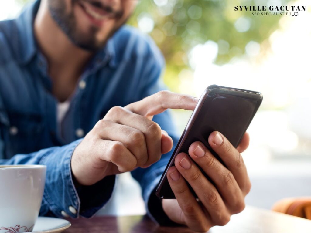 A man smiling while looking at his phone.