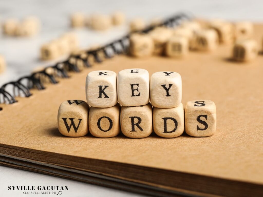 Wooden blocks spell "KEY WORDS" on a notebook.