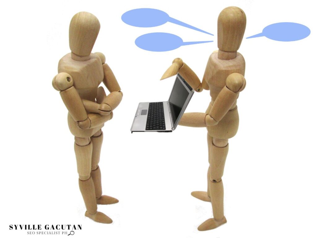 Two wooden figures interacting with a laptop, blue thought bubbles above.