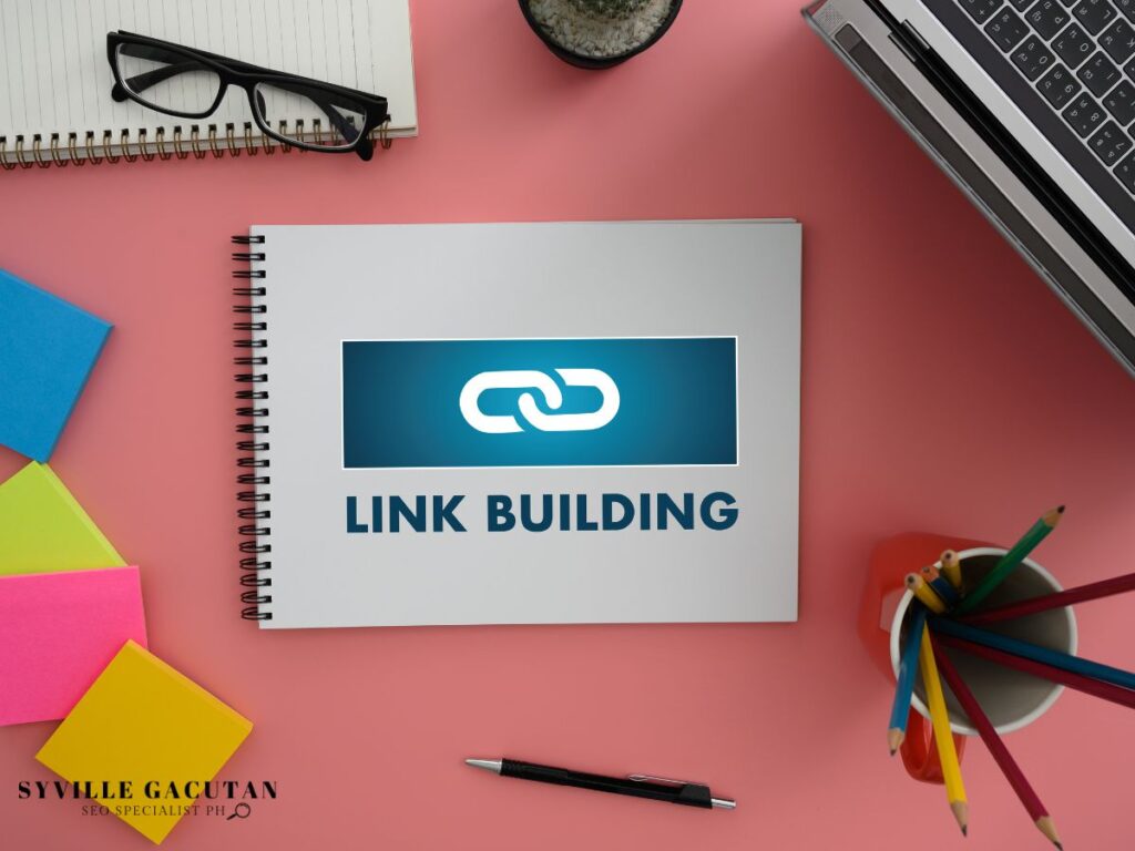 Notebook with "LINK BUILDING" on cover, surrounded by office supplies