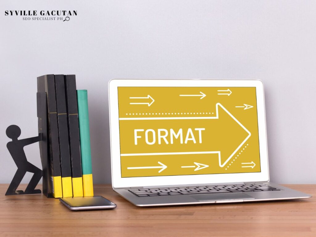 Laptop with "FORMAT" arrows on the screen next to books and a phone
