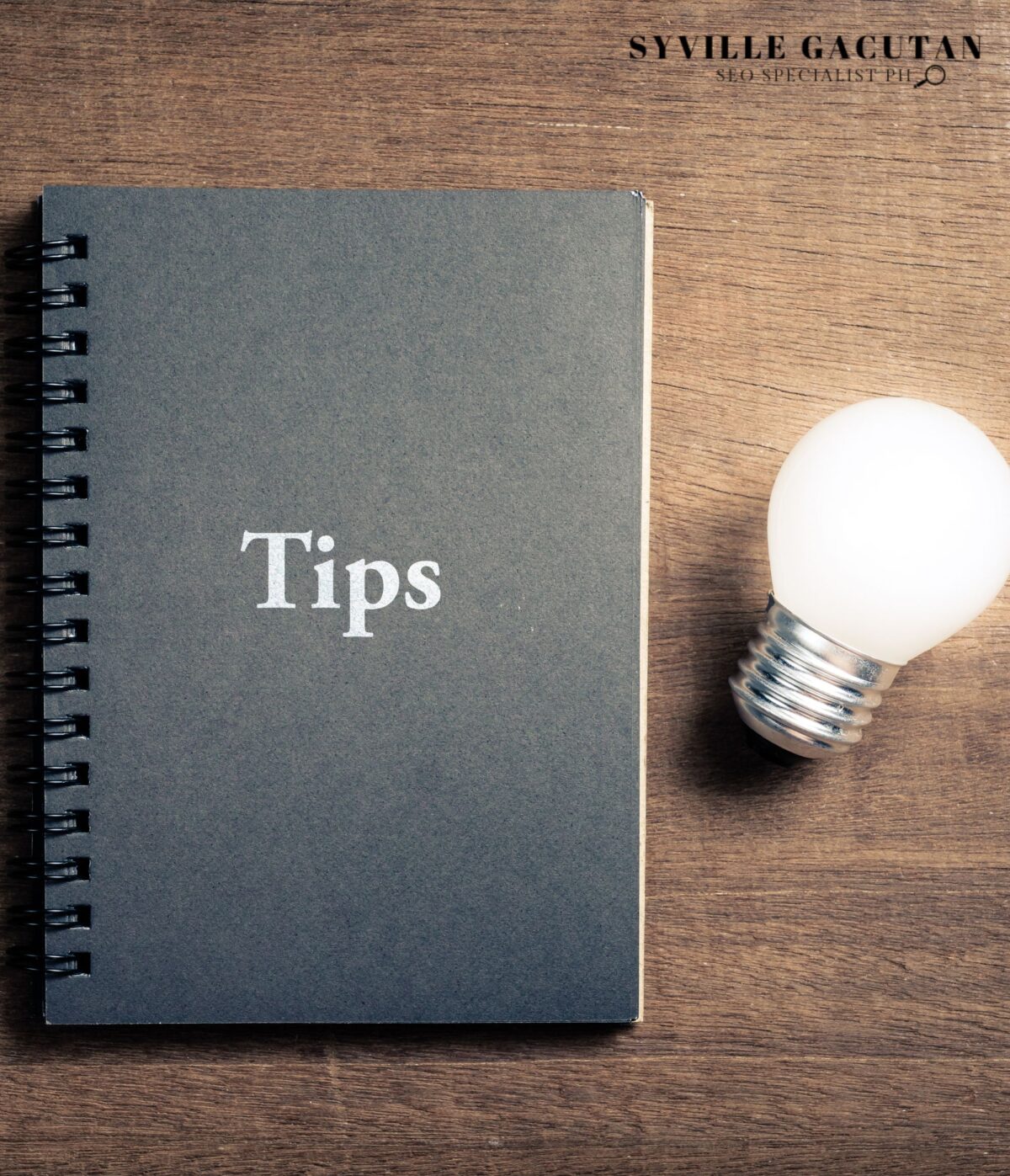 "Tips" notebook beside light bulb on wood.