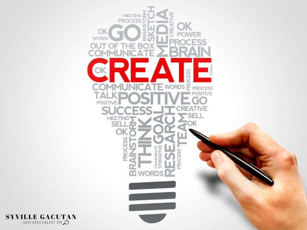 A lightbulb made up of random words with "CREATE" being highlighted and hand holding a pen.