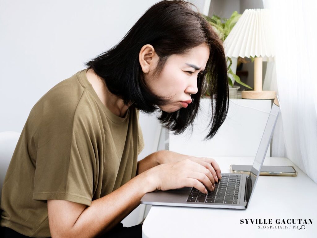 Woman squinting and leaning close to a laptop.