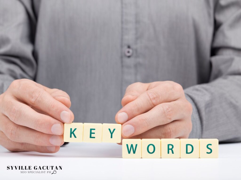 A person assembling the word "KEYWORDS" using letter blocks.