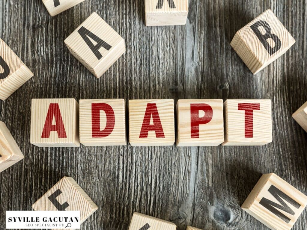 Wooden blocks spelling "ADAPT" on a rustic wooden surface.