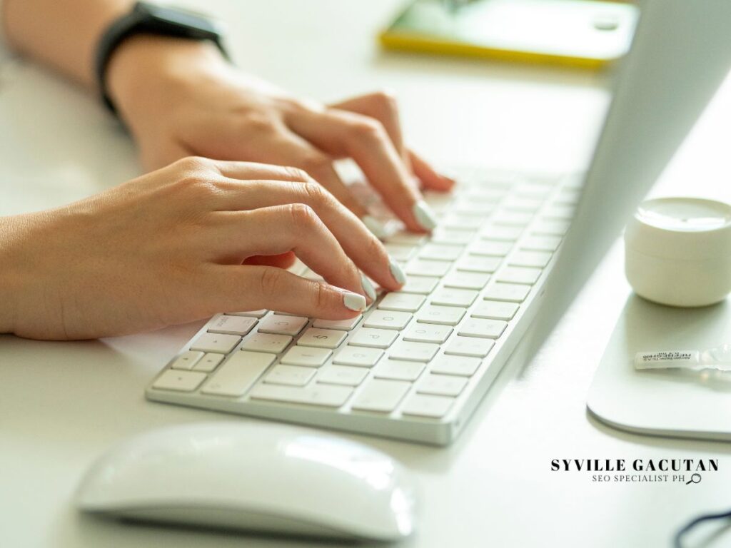 A woman's hand typing on a laptop.