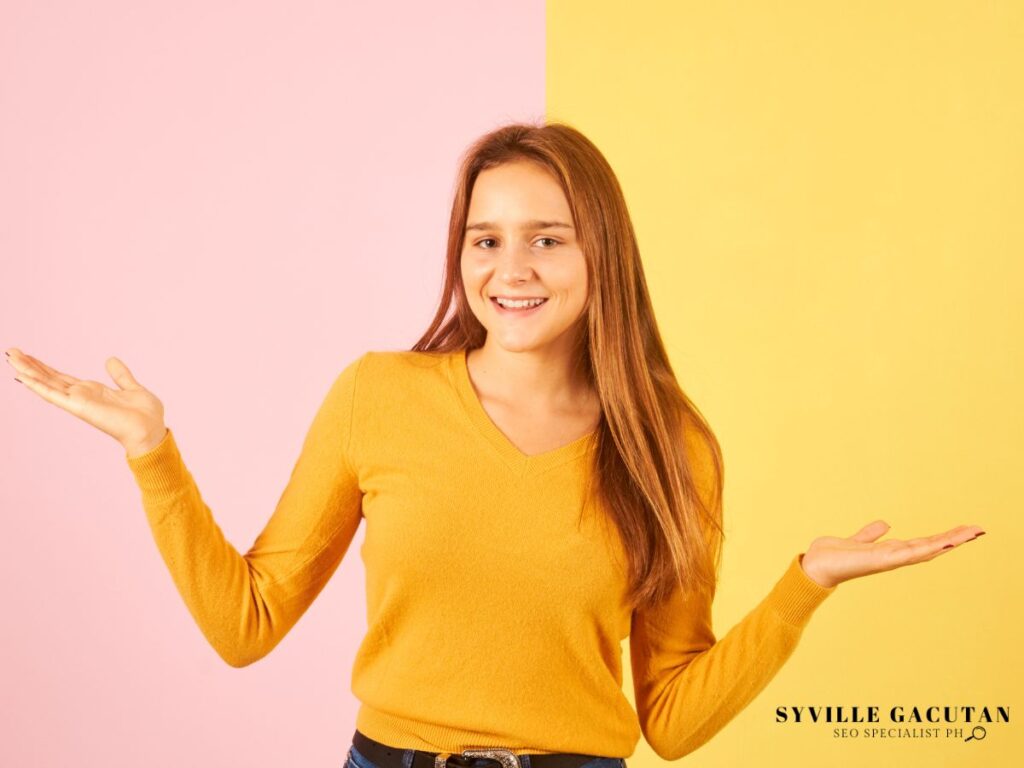 Smiling woman in yellow, shrugging with arms out.