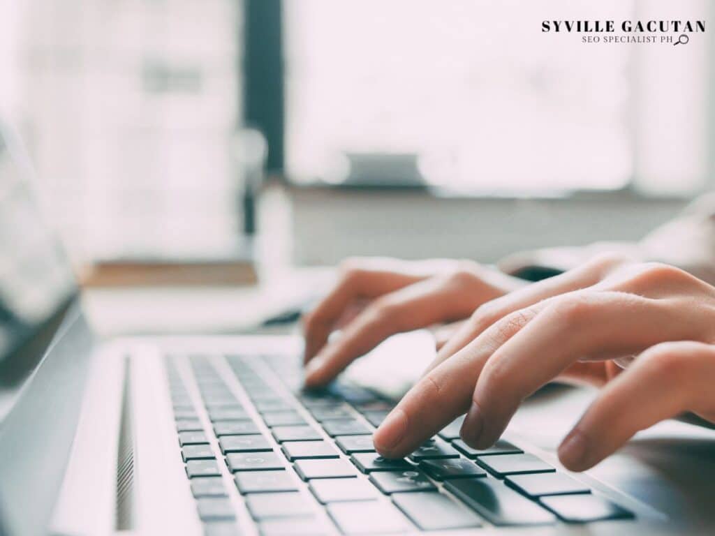 Hands typing on a laptop keyboard.