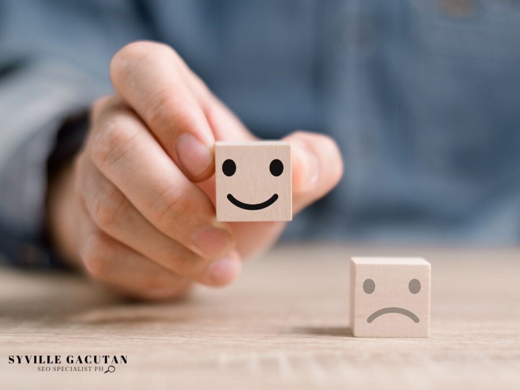 Hand holding a block with a smiley face, next to a sad face block.