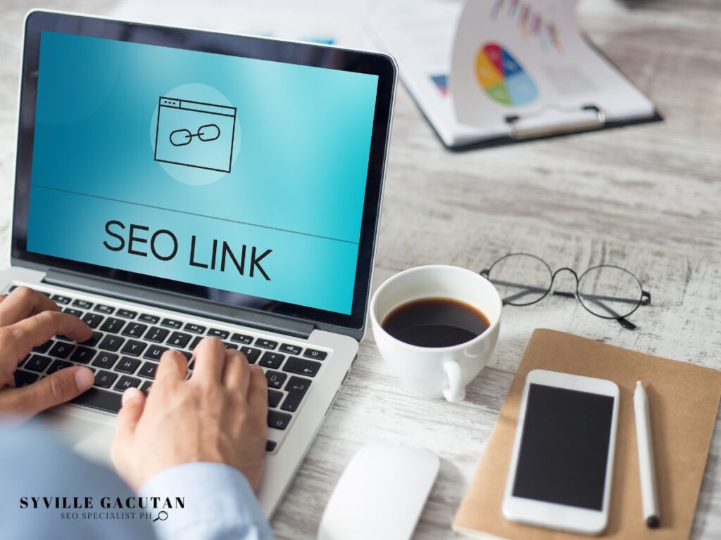 Laptop displaying "SEO LINK" with coffee and glasses nearby.