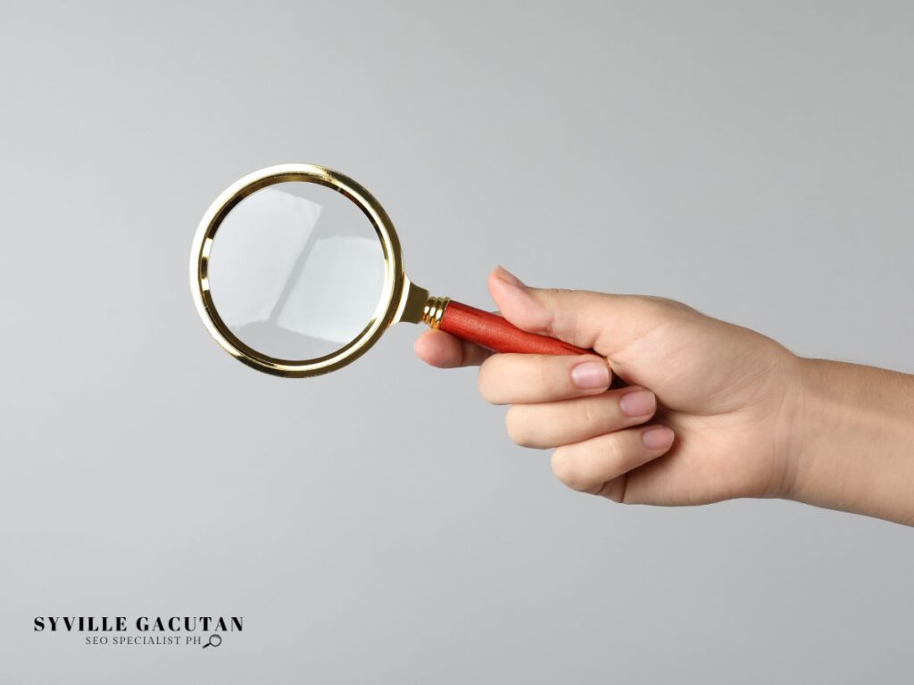 A hand holding a magnifying glass.