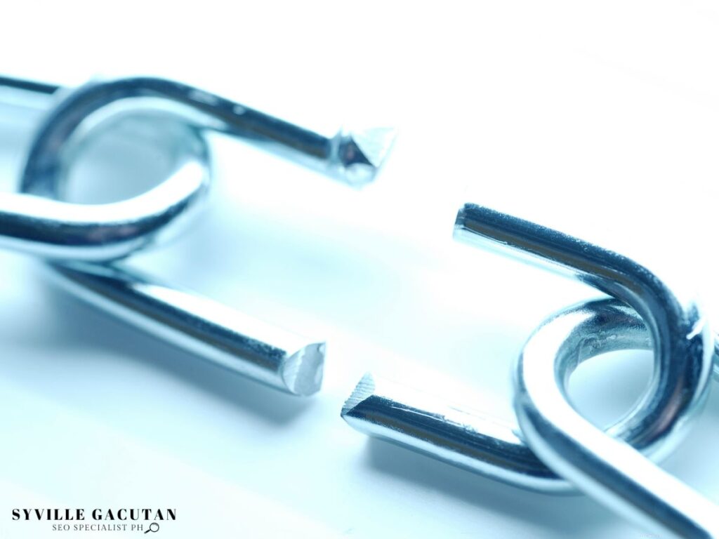 A close-up of a broken metal chain link on a light background.