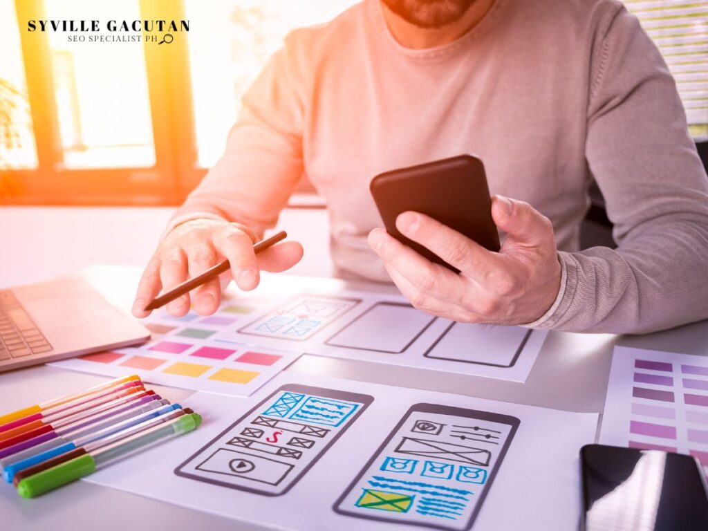 Person sketching app layouts on paper while holding a smartphone.