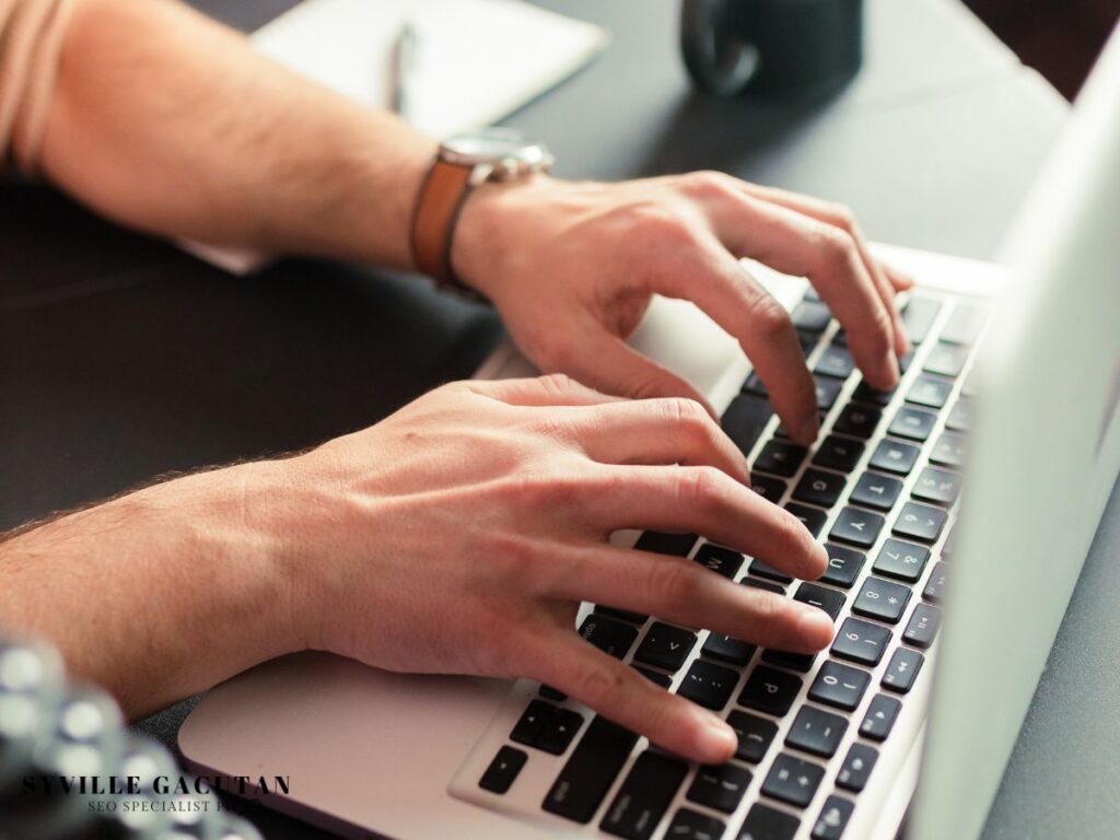 Close-up of hands typing on a laptop keyboard.