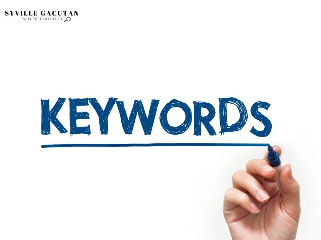 "KEYWORDS" written in blue marker with a hand holding the marker.