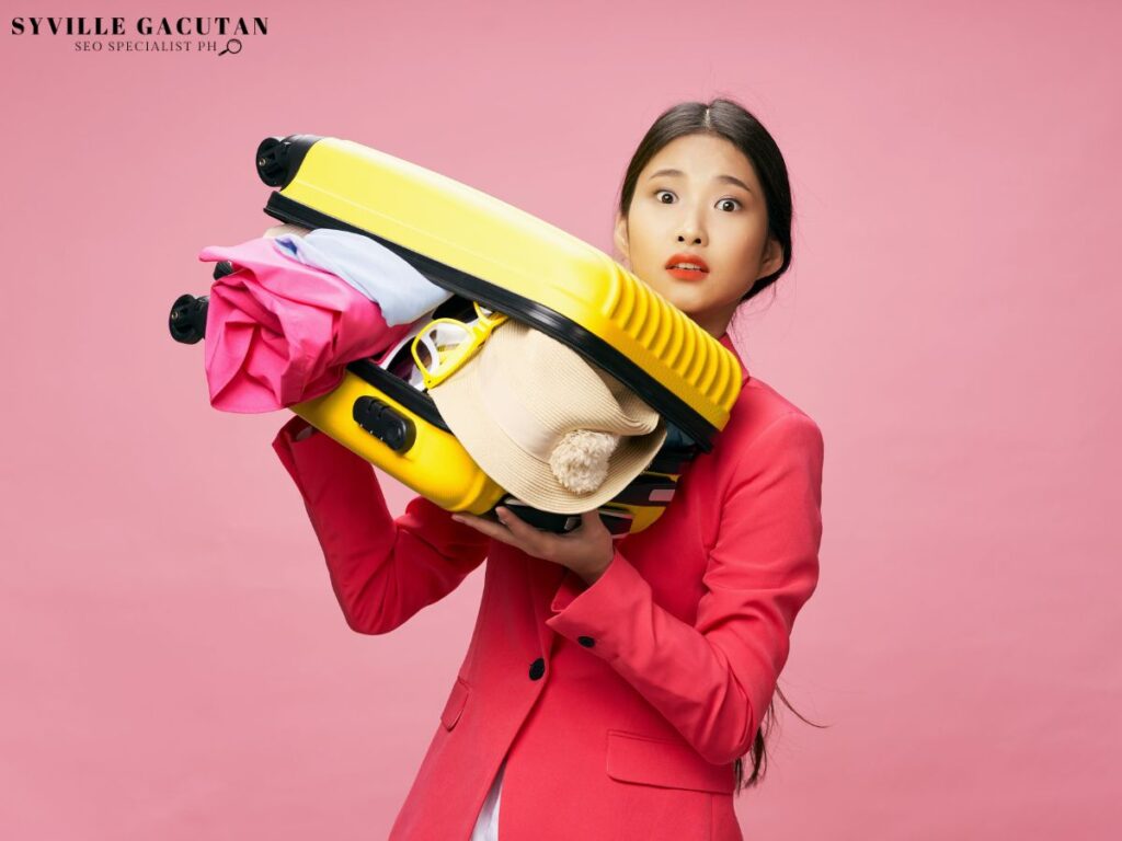 Woman in a pink suit holding an overstuffed yellow suitcase, looking surprised.