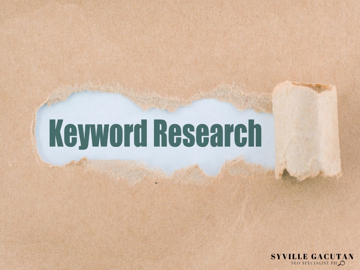 "Keyword Research" revealed through torn paper on a beige background.