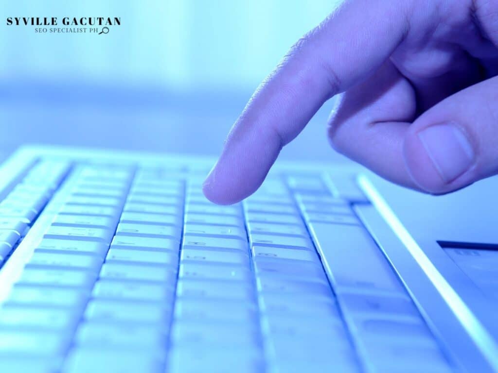 A finger about to press a key on a keyboard.