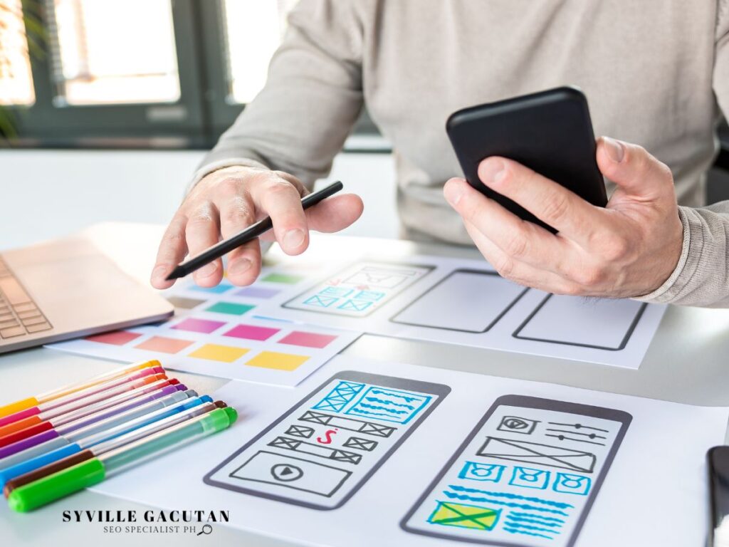A person designing a mobile layout with colored pens and sketches.