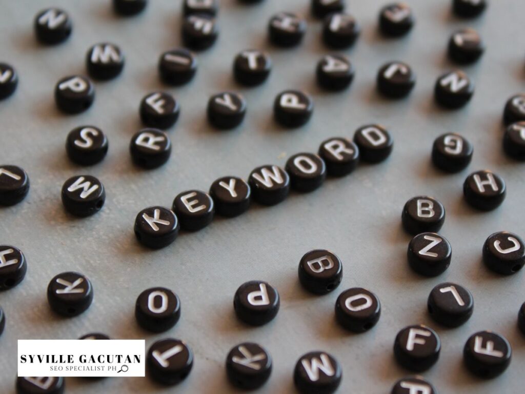 The word "KEYWORD" is spelled out using black circular tiles amidst scattered letters.