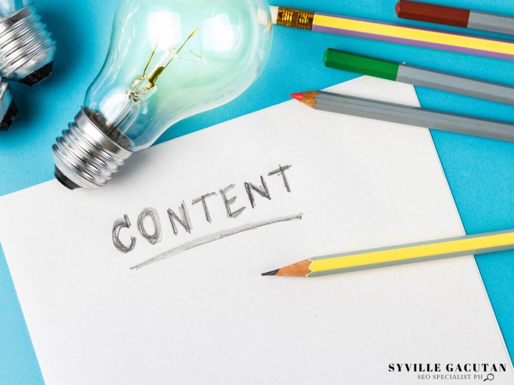 A paper with the word "CONTENT" written on it surrounded by lightbulb and pencils.