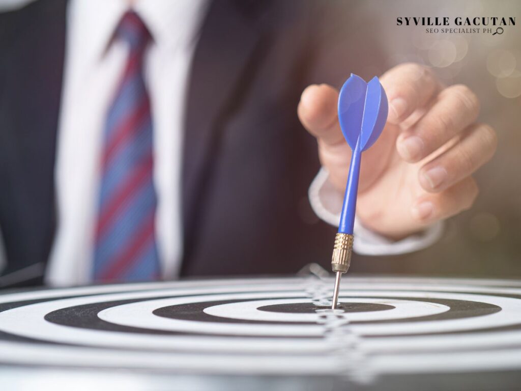 A hand holding a dart aiming at a target's bullseye.