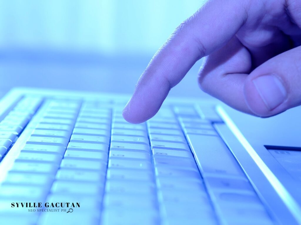 A hand pressing the keyboard keys of laptop.