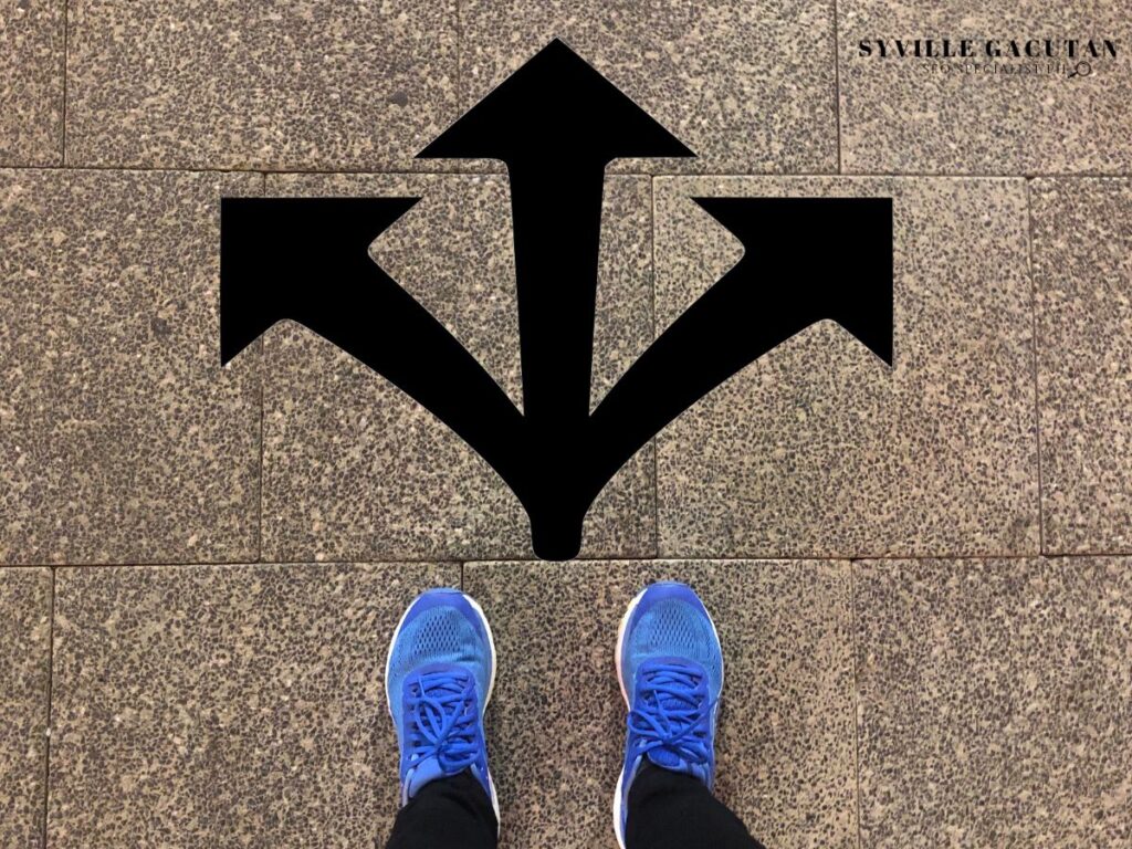 A person standing at a three-way directional arrow on the ground.