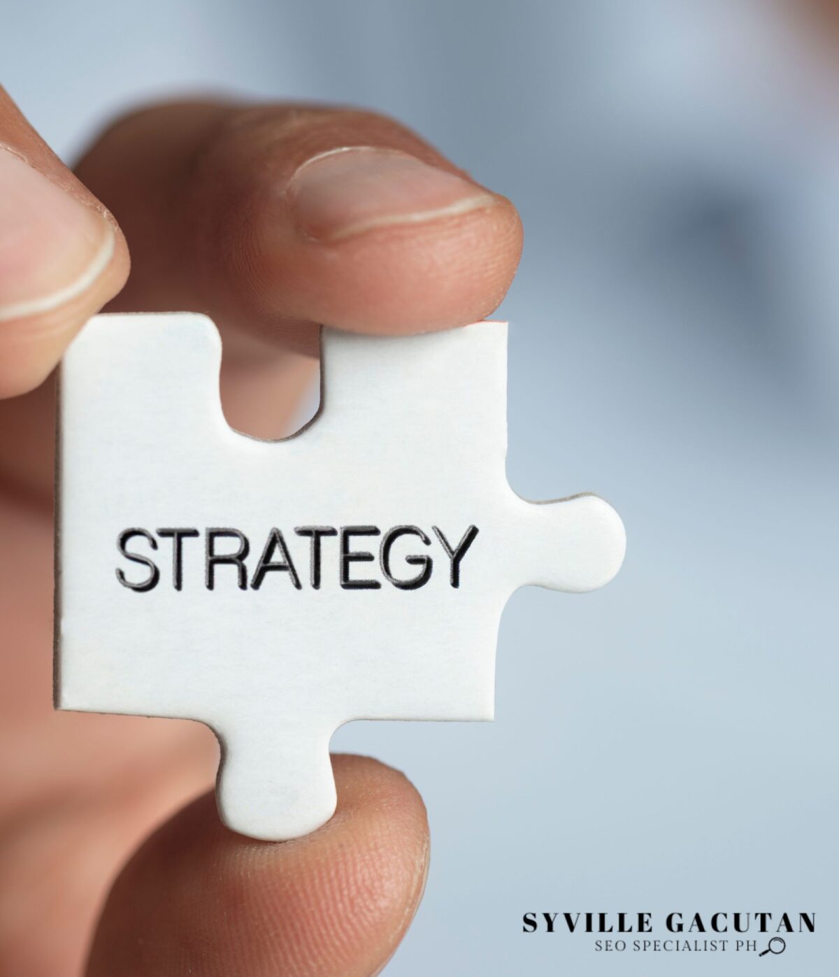 A close up of hand hand holding a puzzle piece labeled as "STRATEGY"