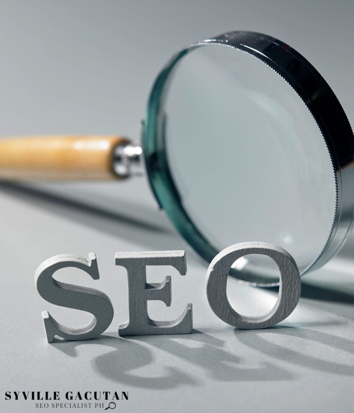 Magnifying glass with SEO letters on gray background.