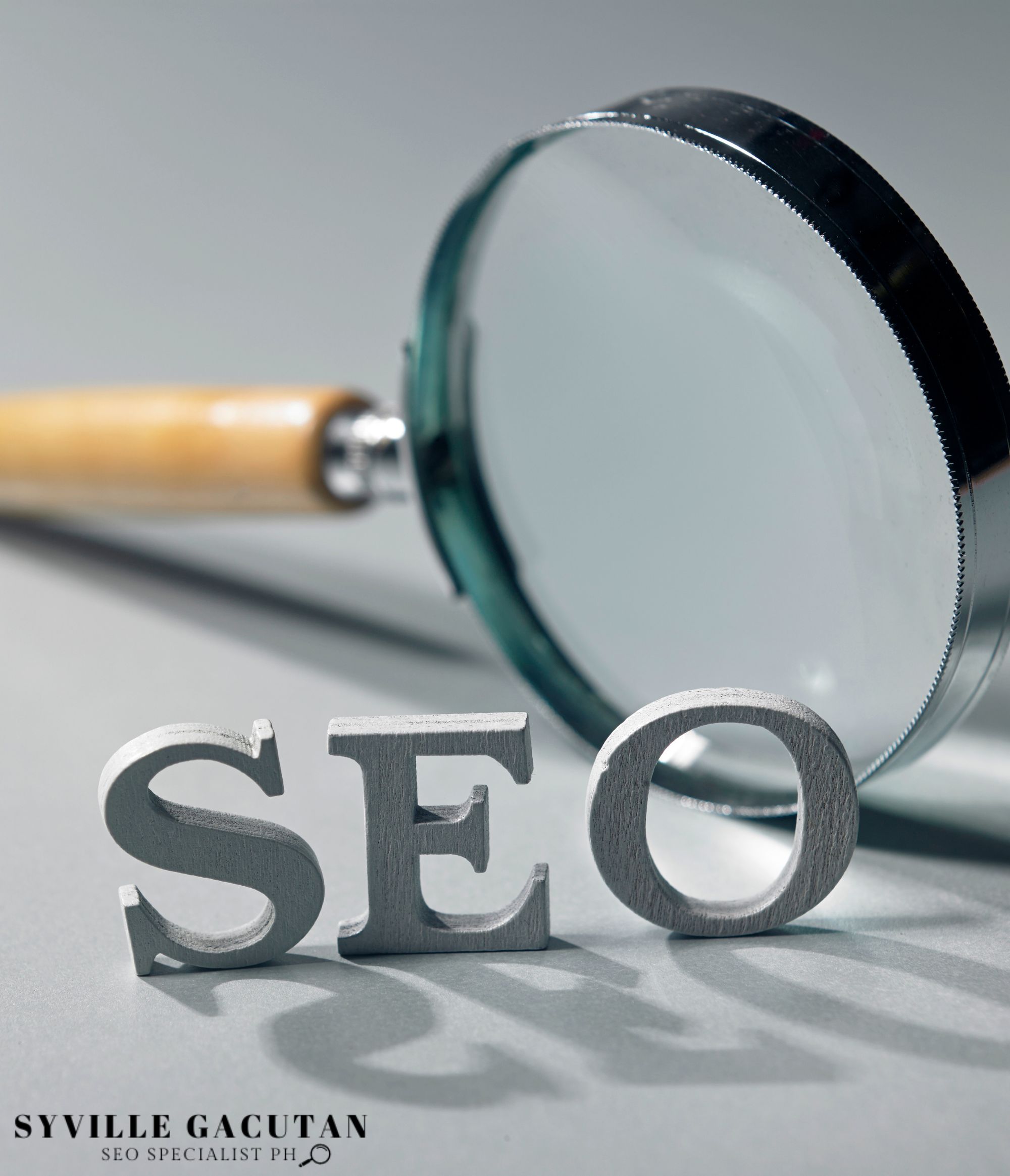Magnifying glass with SEO letters on gray background.