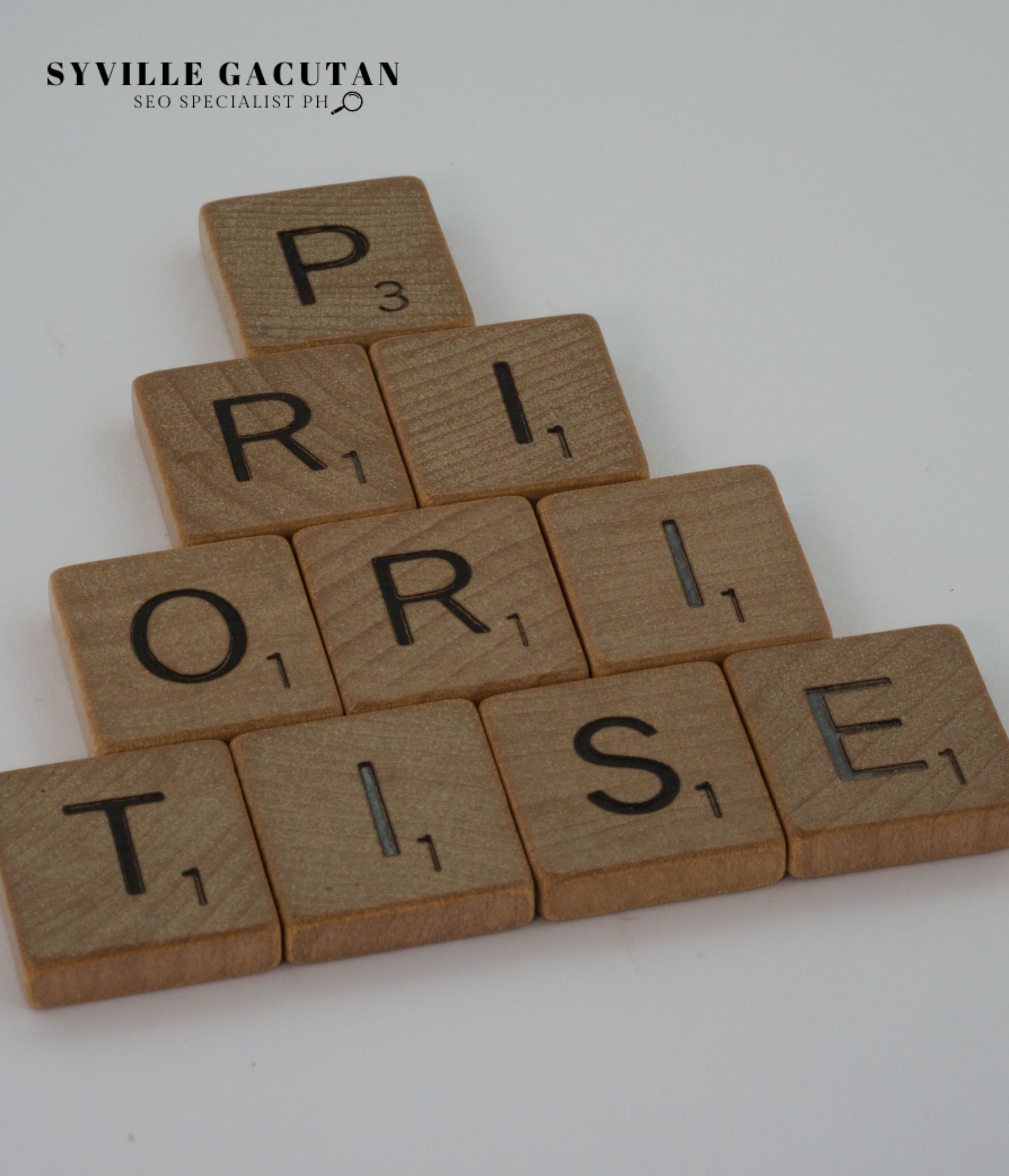 Wooden tiles arranged to spell 'PRIORITISE' in a pyramid shape.