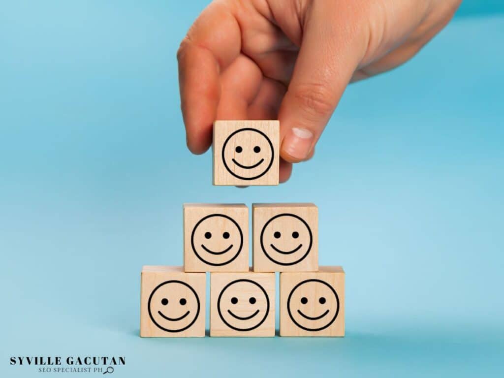 Hand stacking wooden blocks with smiley faces, forming a happy pyramid.