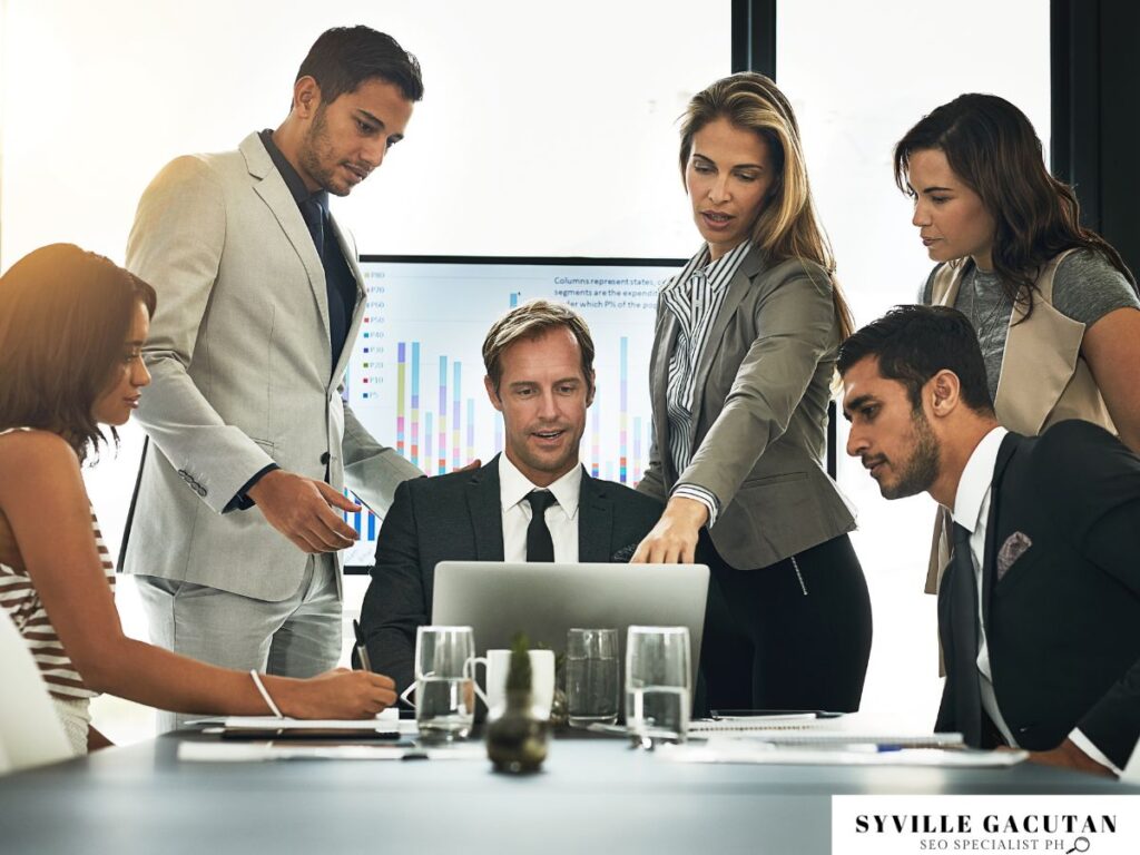 Team collaborating around a laptop in a professional setting.