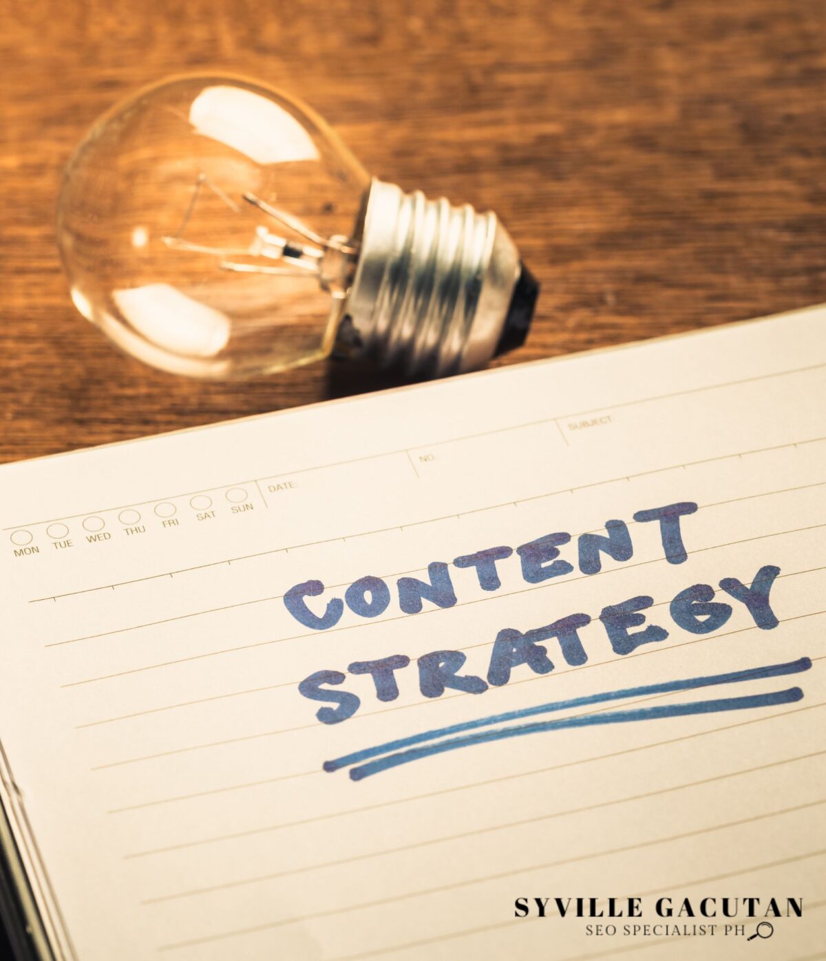 A lightbulb rests on a wooden surface beside a notebook page titled "CONTENT STRATEGY" in blue text.