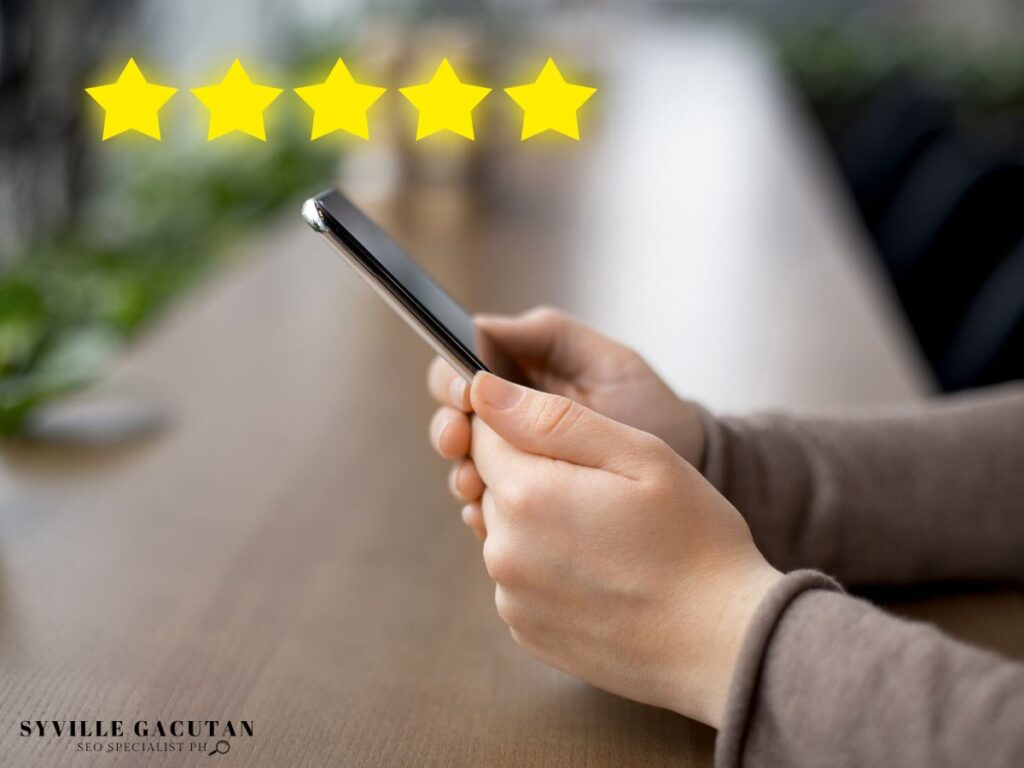 Hands holding a smartphone with five yellow stars floating above on a blurred background.