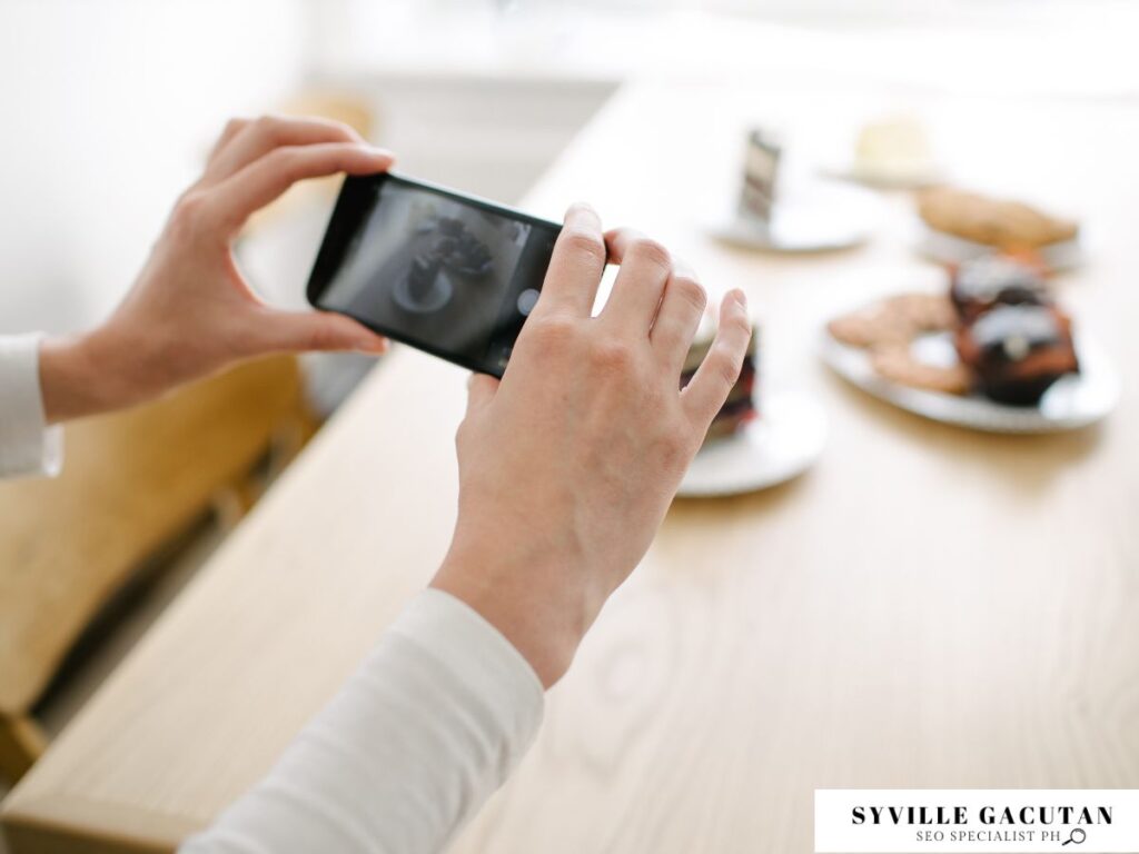 Person photographing food on a table using a smartphone.