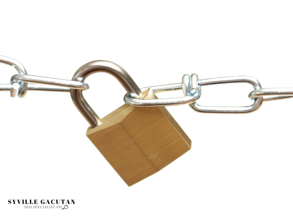 Gold padlock secured on metal chain links against white background.