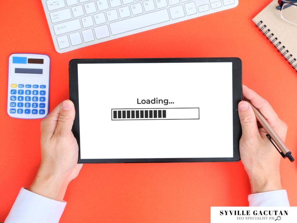 Tablet showing loading progress bar on red desk with calculator and keyboard.