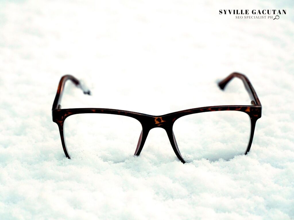 Tortoiseshell eyeglasses frames resting on pure white snow, creating a minimalist contrast.