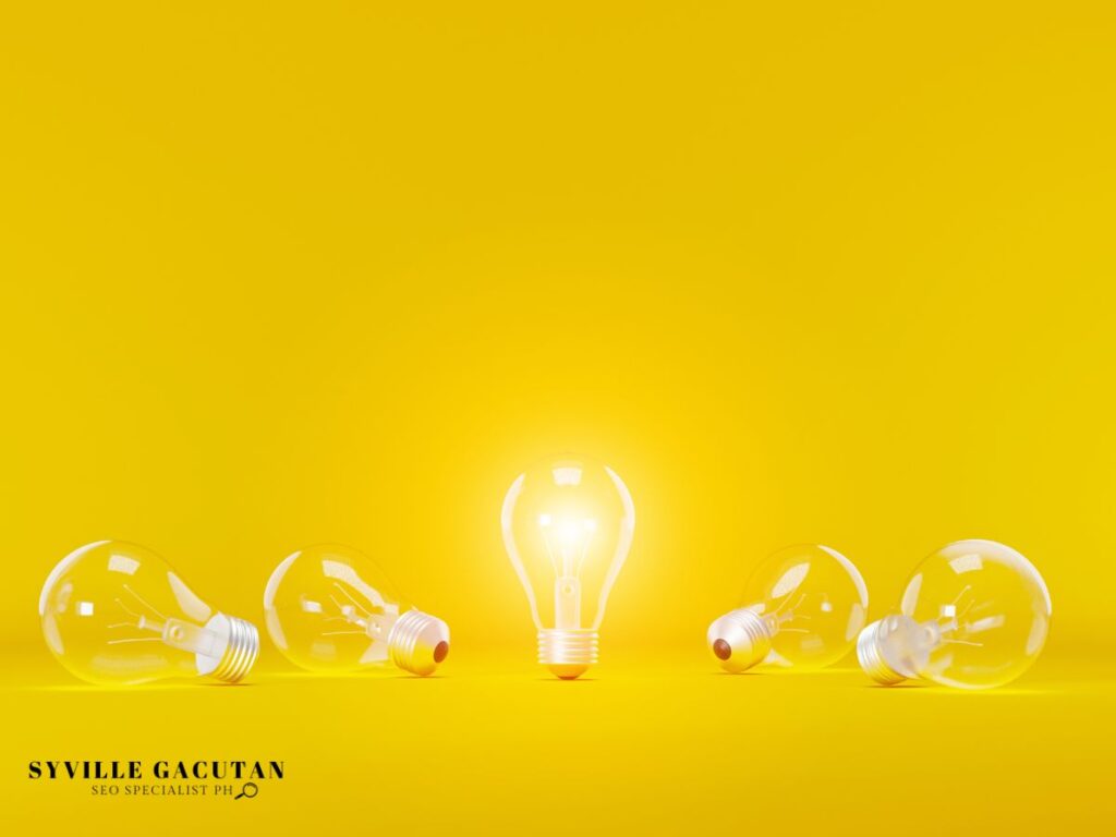 One glowing lightbulb standing upright among fallen bulbs on vibrant yellow background.