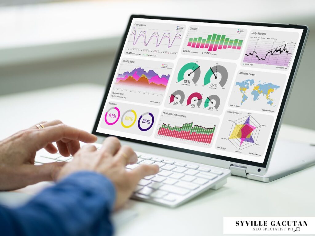 Hands typing on a laptop displaying colorful data dashboards.