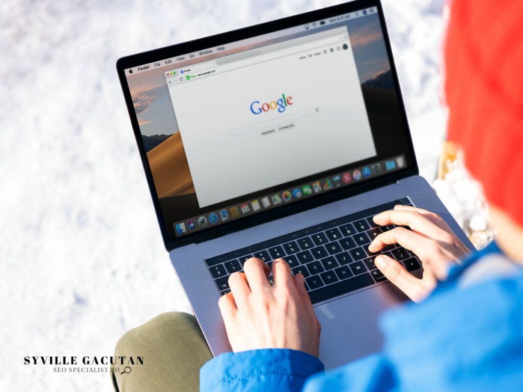 Person browsing on a laptop with the Google homepage displayed.