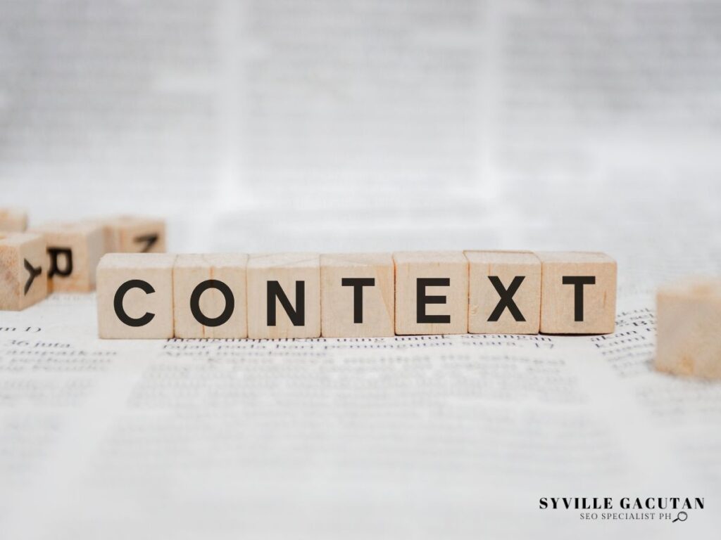 Wooden letter tiles spelling out "CONTEXT" on white textured paper surface.