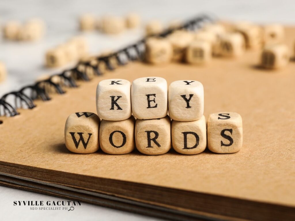 Wooden blocks spelling "KEYWORDS" on a notebook.