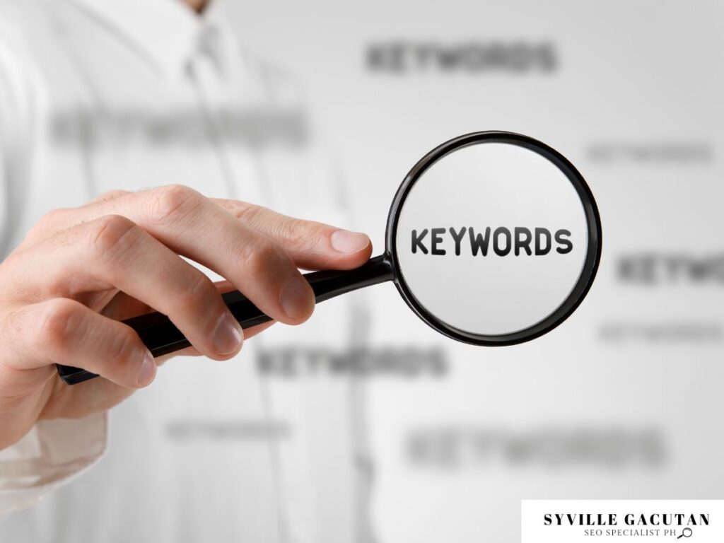 Hand holding a magnifying glass over the word "Keywords."