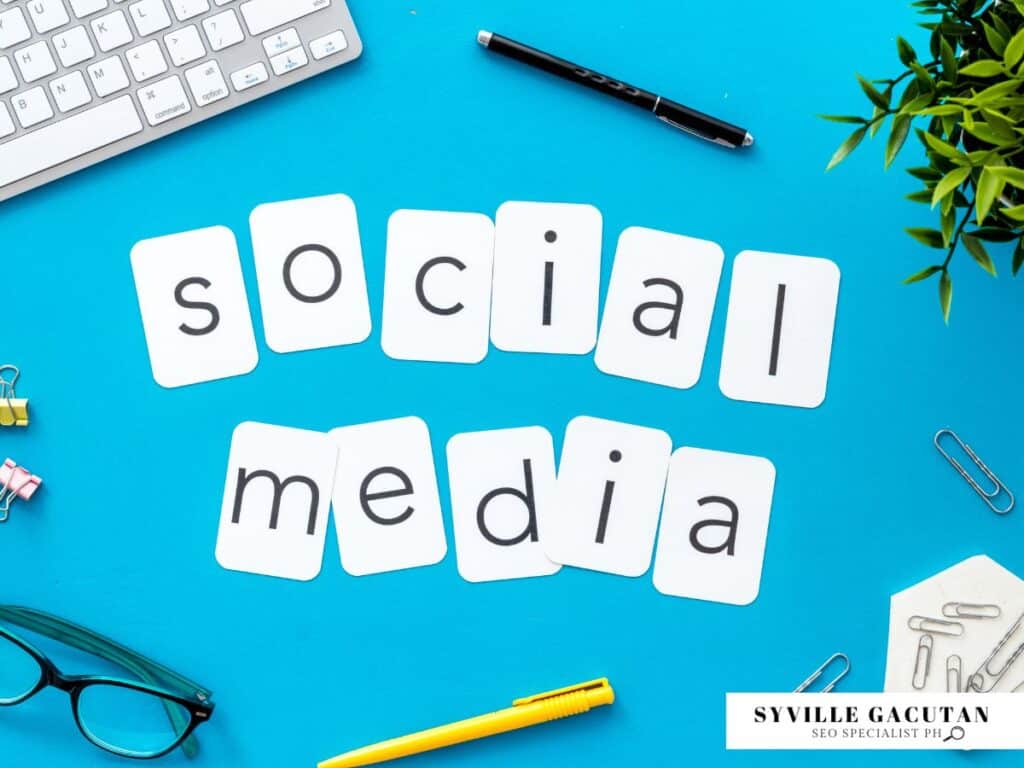 "Social Media" spelled on white cards with office items on a blue background.