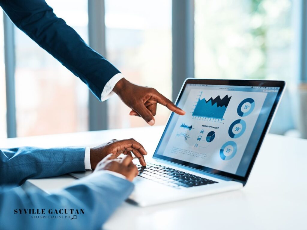 Businessman pointing at a laptop with data charts on the screen.